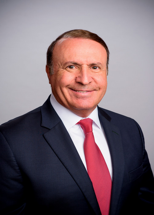 Dr. Swaid sits in a black suit with a red tie against a black background