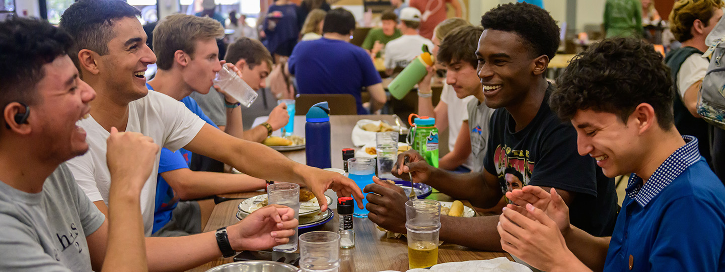 Students laughing around a table during lunch