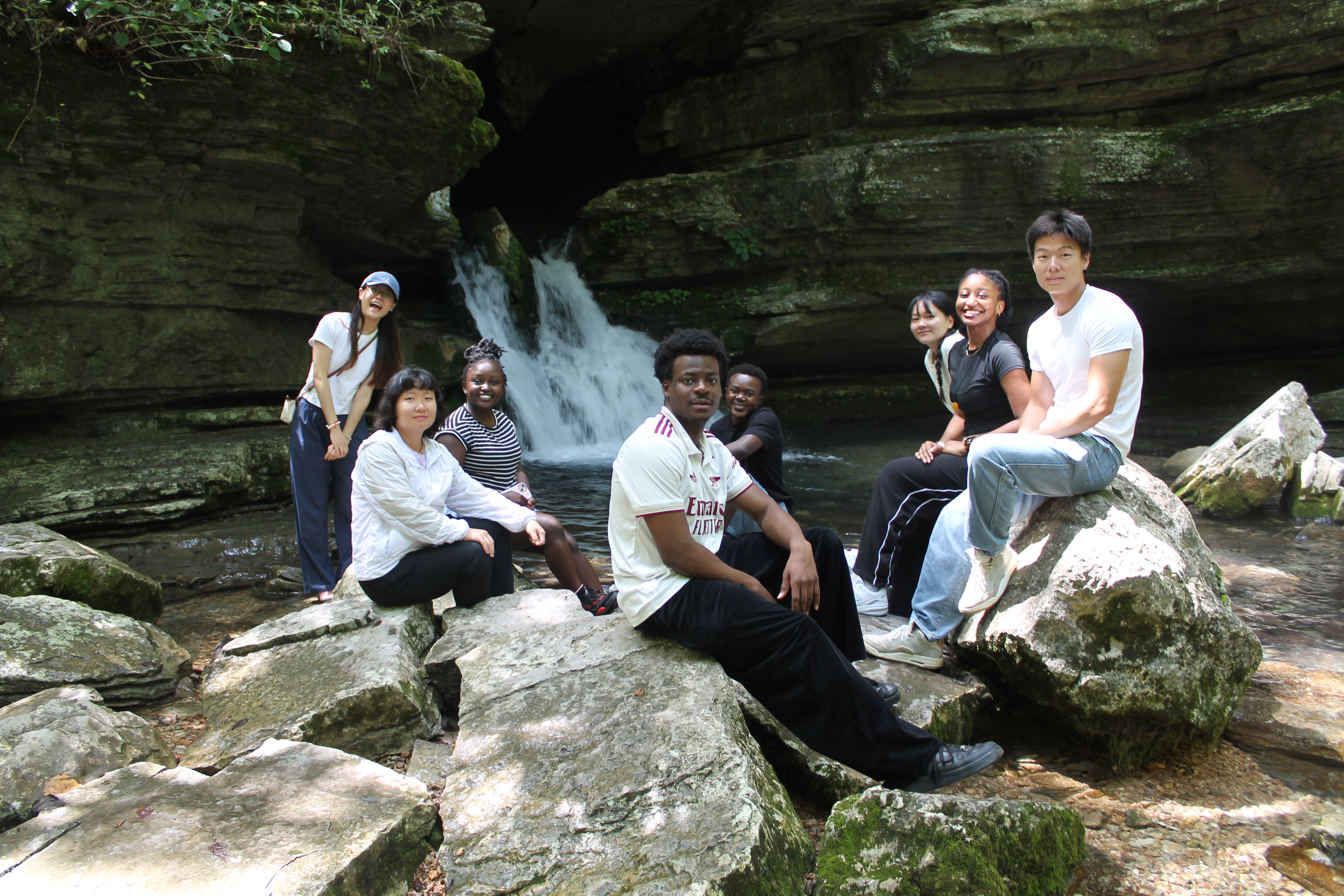 Students in front of rocks and a waterfall