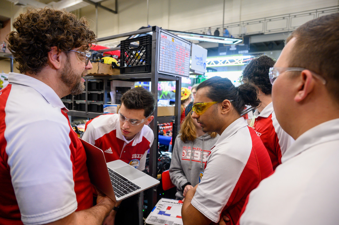 robotics team huddled around a computer, debating.