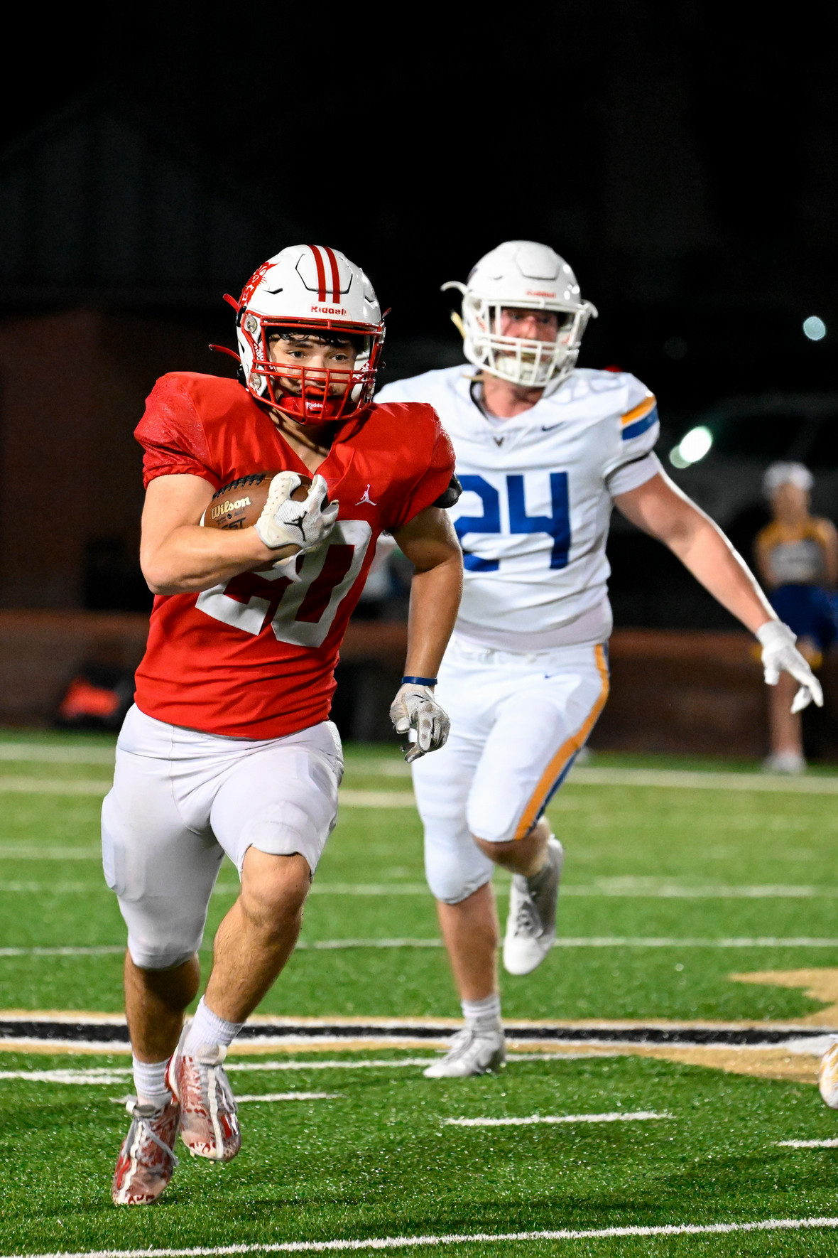 Football player, number 20, running away from a defender, number 24