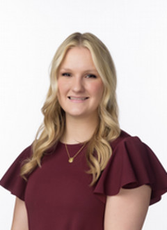 Haley wearing a maroon top, smiling in a studio portrait against a white background.
