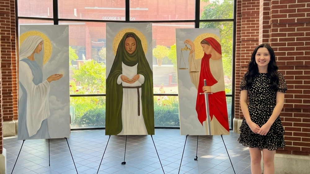 Jordan standing beside her three paintings
