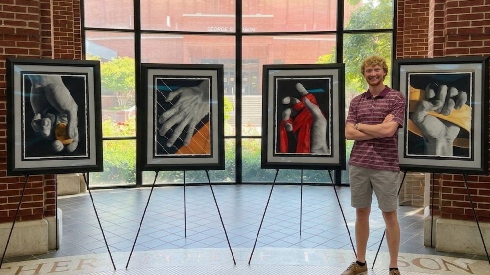 Cooper standing beside his three paintings