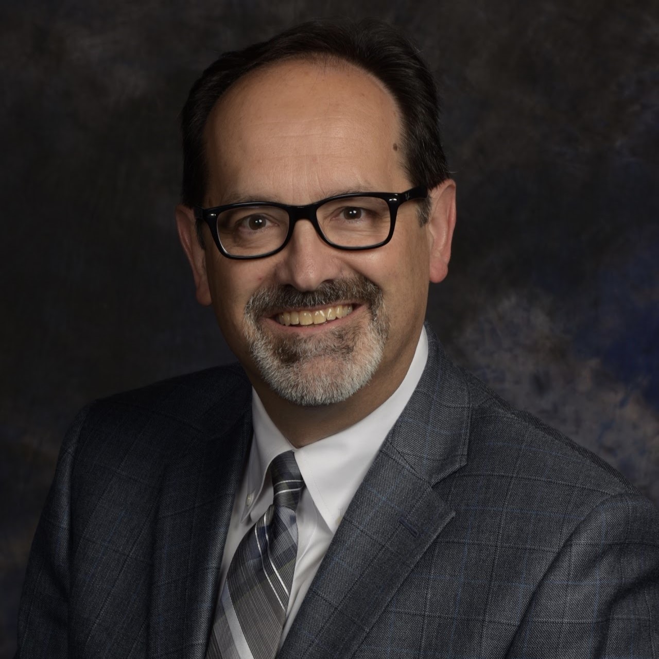 Dr. Bill T. Arnold smiles in glasses and a gray suit