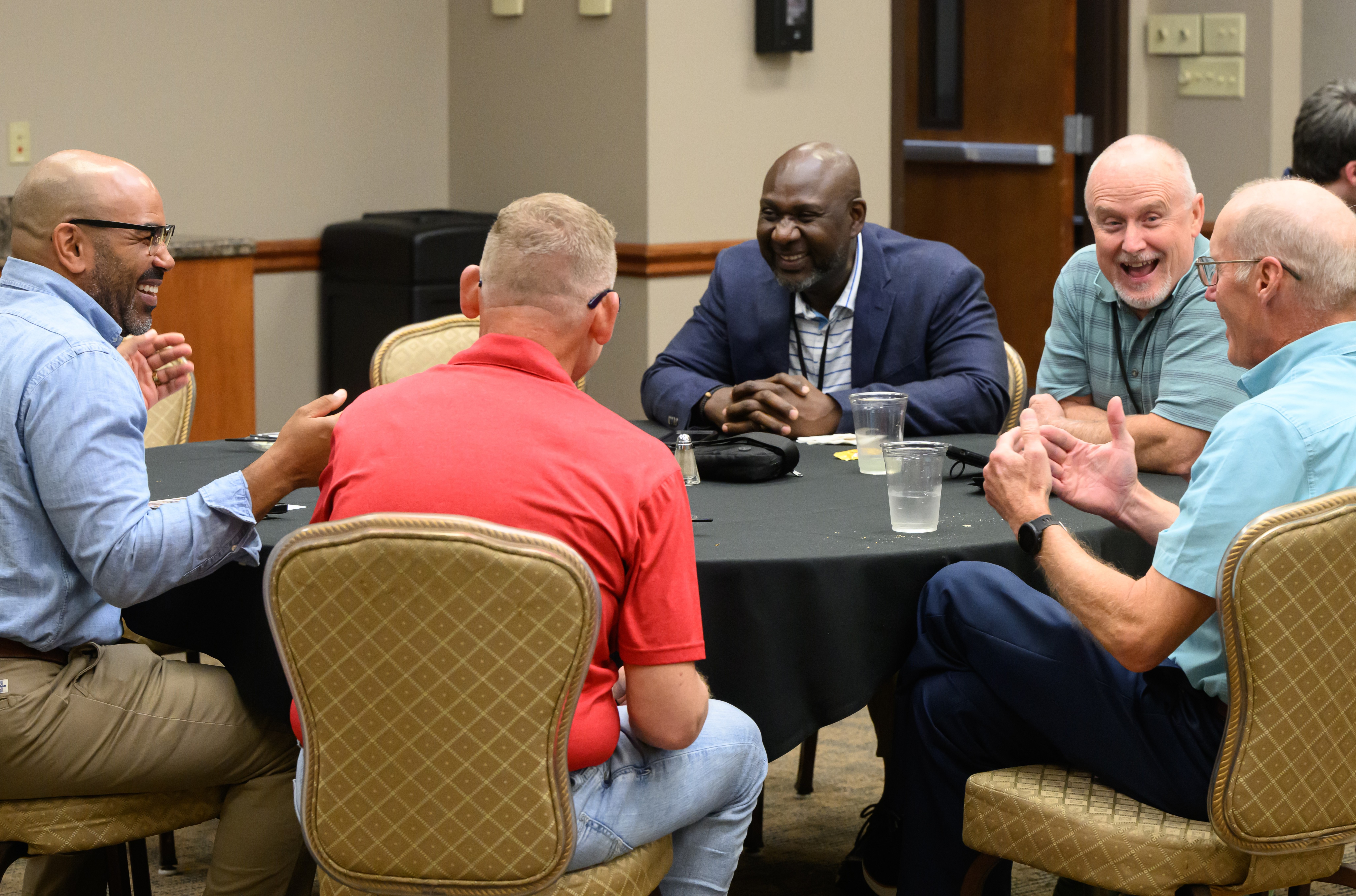 Dave Bland, Jason Darden and others laugh around a around table