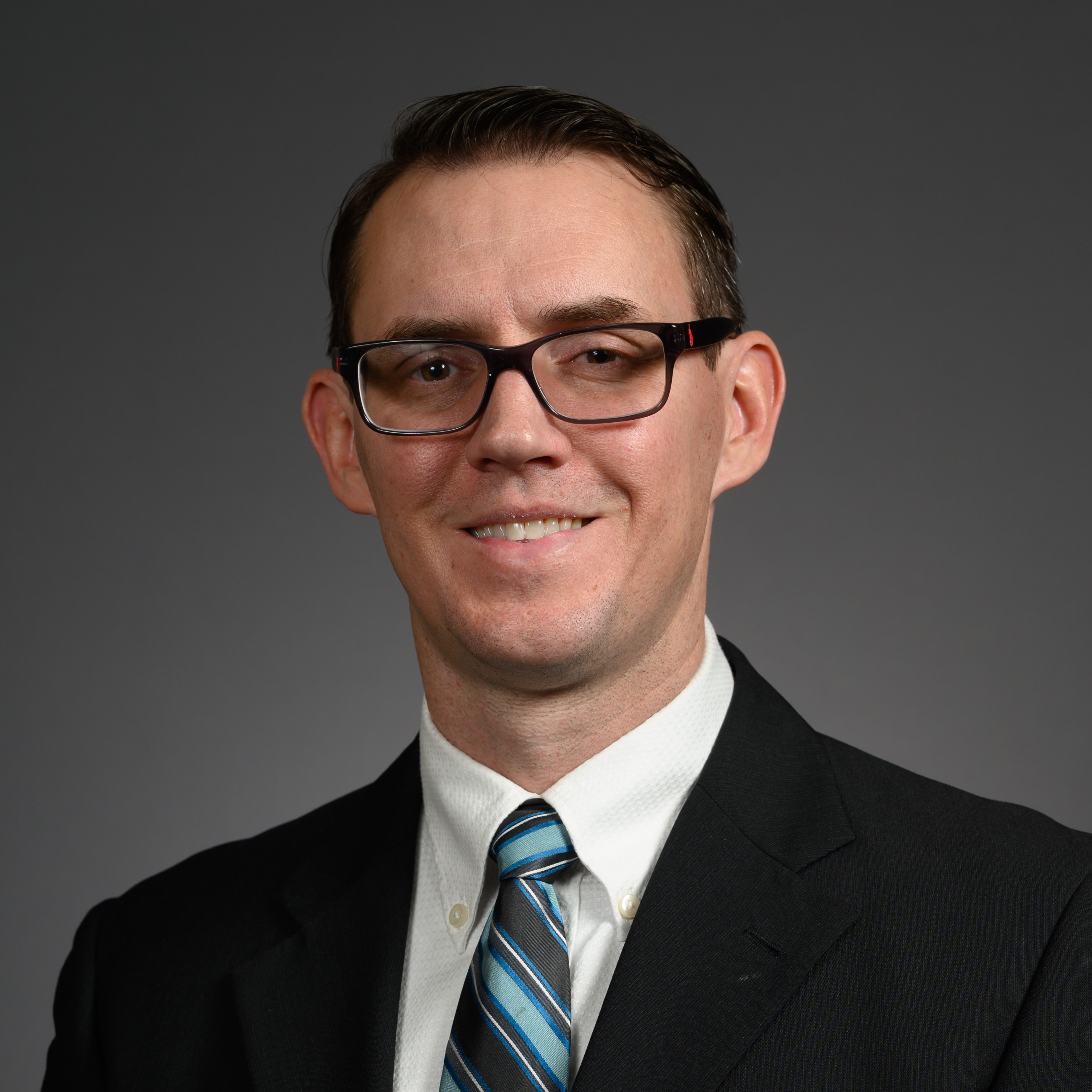Peter Rice smiles in glasses and blue striped tie