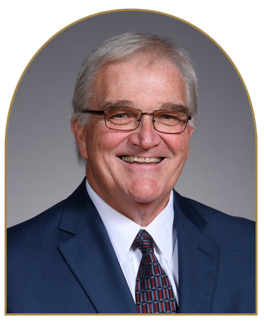 Dr. Phil Thompson smiling while wearing glasses and a blue suit.
