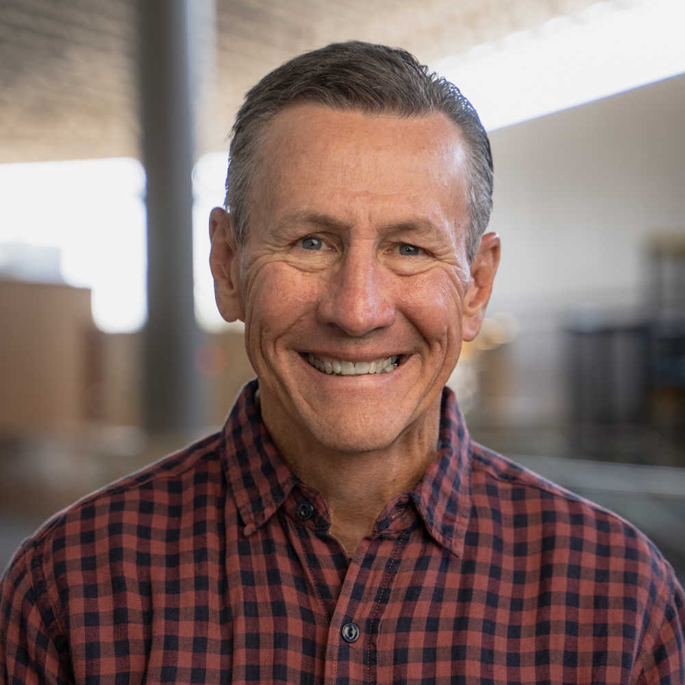 Rick Atchley smiles in a collard red checkerd shirt