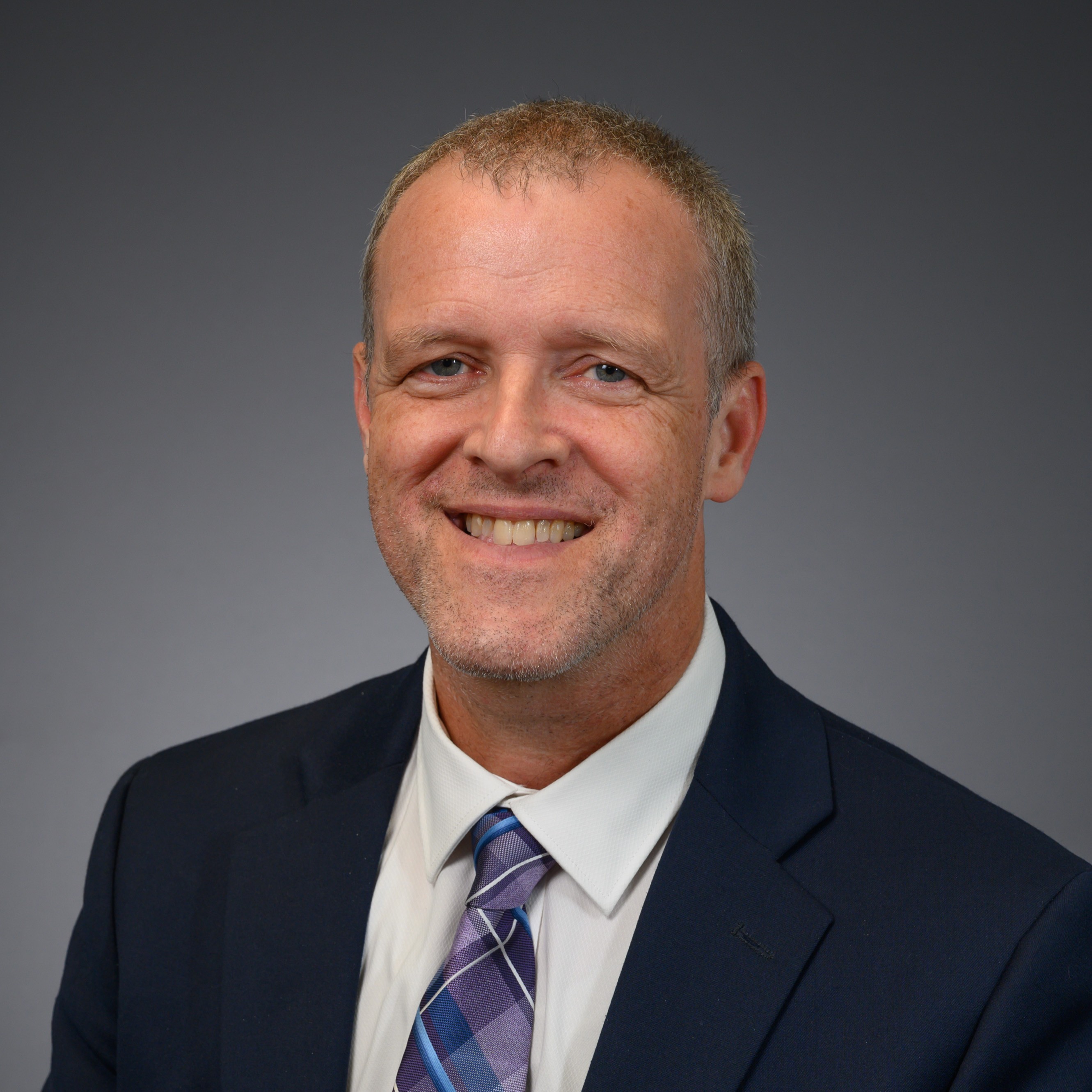 Dr. Kevin Youngblood smiles in a suit