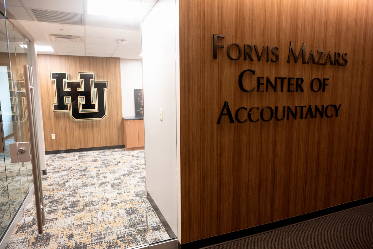 Center of Accountancy main enterance. A Large "H.U." is shown on the wall, and to the right is a sign introducing building