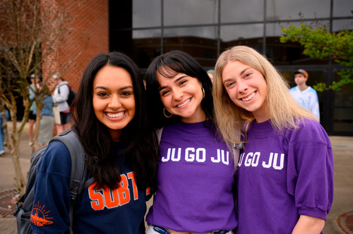 Three students wearing club jerseys are smilies for a group photo.