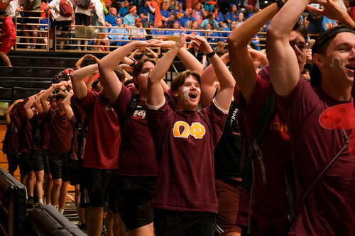 New members of Omega Phi walking into an All-Club event with arms raised to form the letter "O".